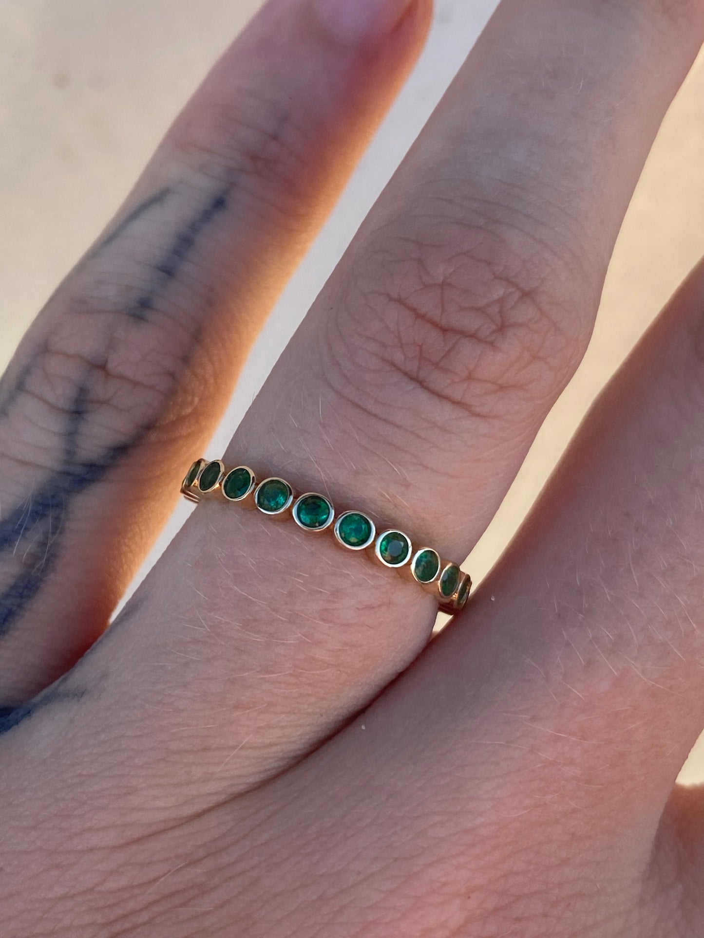14kt .60ctw emerald bezel eternity band